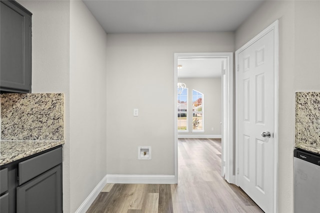 kitchen featuring light stone counters, stainless steel dishwasher, gray cabinets, and light hardwood / wood-style flooring