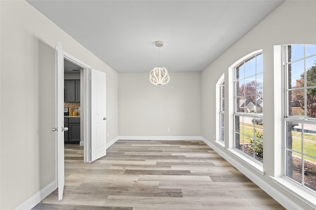 unfurnished dining area featuring light hardwood / wood-style flooring and a chandelier