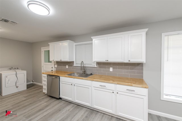 kitchen featuring dishwasher, wooden counters, sink, washing machine and dryer, and white cabinetry