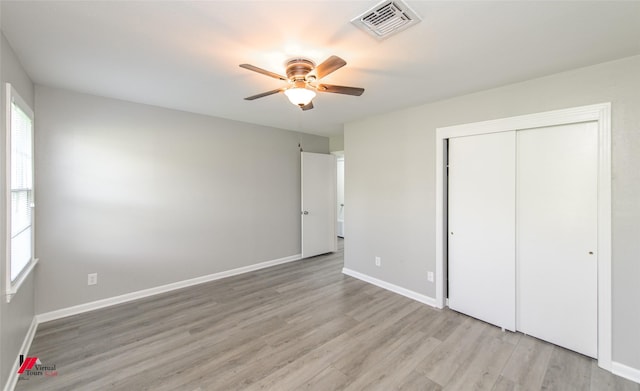 unfurnished bedroom featuring ceiling fan, a closet, light wood-type flooring, and multiple windows