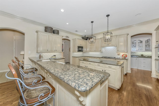 kitchen featuring cream cabinets, a breakfast bar area, dark stone countertops, and decorative backsplash