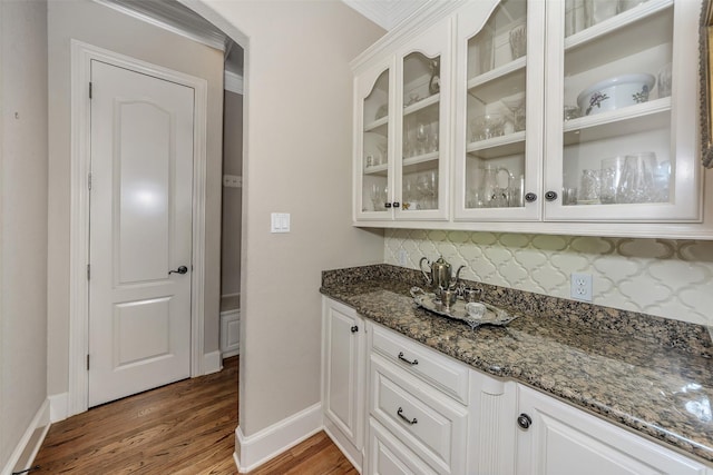 bar featuring decorative backsplash, white cabinets, and dark stone counters