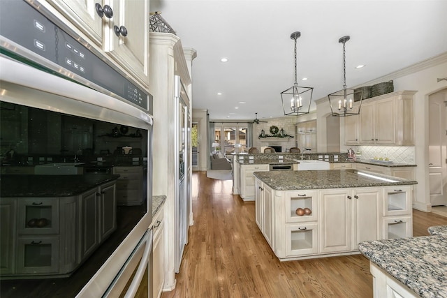 kitchen with a kitchen island, decorative light fixtures, backsplash, light stone countertops, and stainless steel double oven