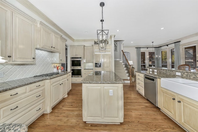 kitchen featuring decorative light fixtures, a chandelier, a center island, dark stone countertops, and appliances with stainless steel finishes