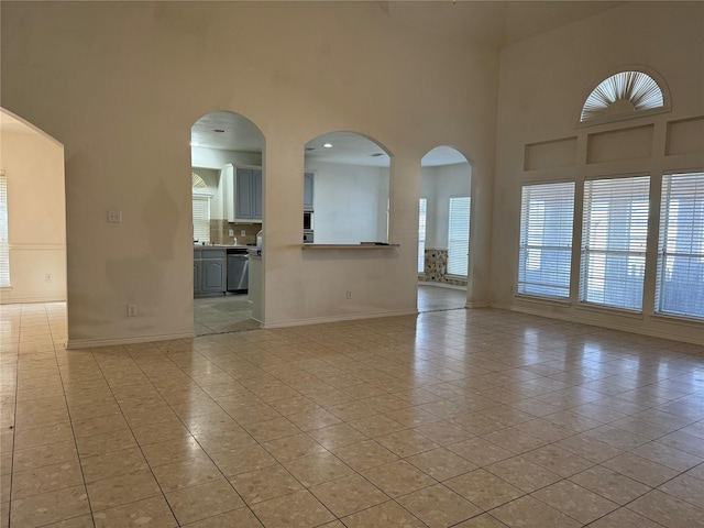 empty room with a high ceiling and light tile patterned flooring