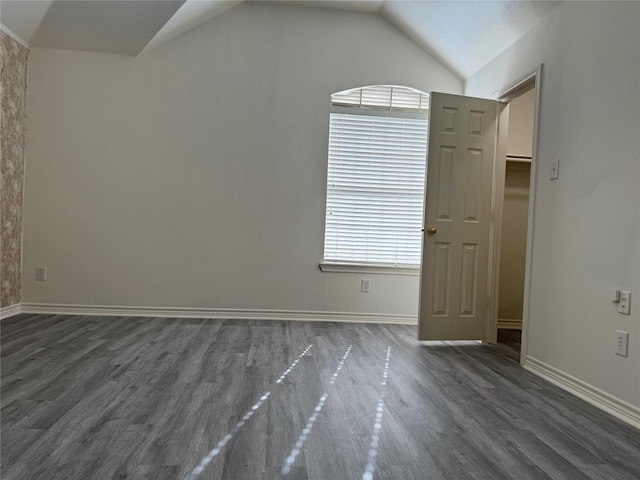 empty room with dark hardwood / wood-style flooring and vaulted ceiling