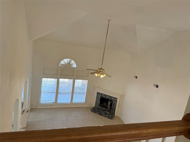 unfurnished living room with ceiling fan, a fireplace, high vaulted ceiling, and light tile patterned flooring