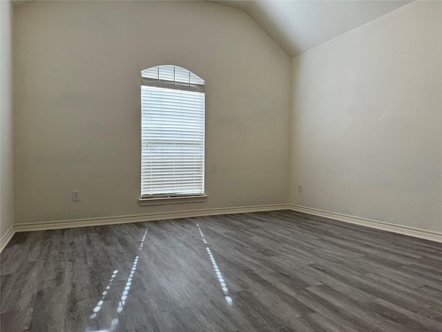 spare room featuring dark wood-type flooring and vaulted ceiling