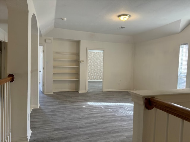 unfurnished room with built in shelves and hardwood / wood-style floors