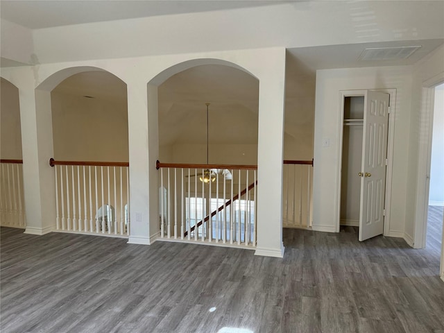 unfurnished room with dark hardwood / wood-style floors, lofted ceiling, and a chandelier