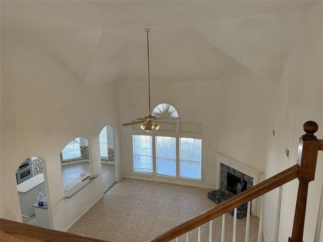 unfurnished living room featuring a healthy amount of sunlight, light colored carpet, a premium fireplace, and high vaulted ceiling