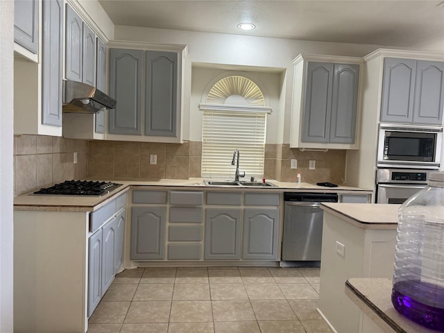 kitchen with sink, stainless steel appliances, gray cabinets, decorative backsplash, and light tile patterned floors