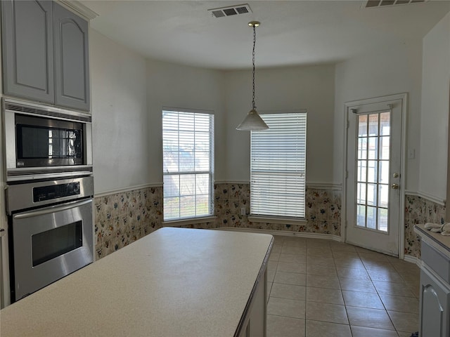 kitchen with light tile patterned floors, hanging light fixtures, and appliances with stainless steel finishes