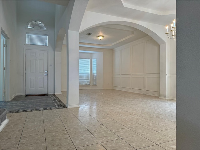 entrance foyer featuring light tile patterned floors, a tray ceiling, and a notable chandelier