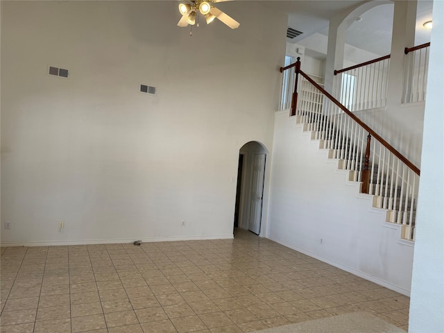 unfurnished living room featuring ceiling fan, a towering ceiling, and light tile patterned floors