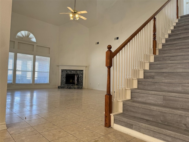 staircase featuring a wealth of natural light, ceiling fan, a fireplace, and high vaulted ceiling