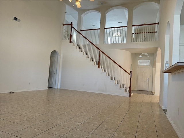 tiled entryway featuring ceiling fan and a towering ceiling