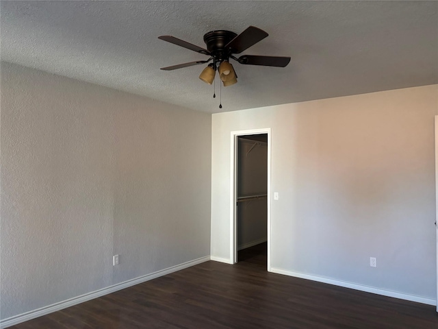 empty room featuring dark hardwood / wood-style floors, ceiling fan, and a textured ceiling