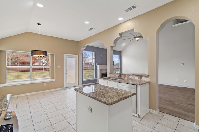 kitchen featuring dishwasher, sink, hanging light fixtures, vaulted ceiling, and white cabinetry