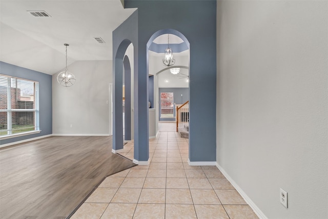 foyer entrance with a chandelier, vaulted ceiling, and light wood-type flooring