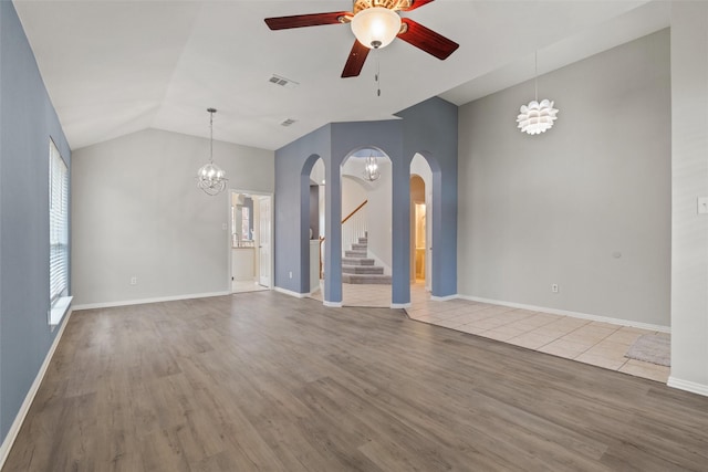 unfurnished living room with ceiling fan with notable chandelier, hardwood / wood-style flooring, and vaulted ceiling