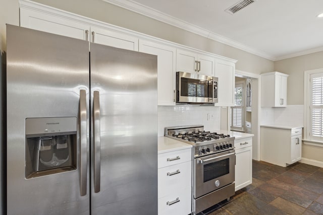 kitchen featuring decorative backsplash, white cabinets, stainless steel appliances, and ornamental molding