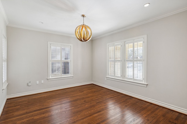 spare room featuring dark hardwood / wood-style floors, a healthy amount of sunlight, ornamental molding, and a chandelier