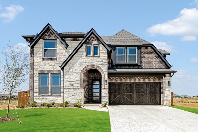 view of front of home featuring driveway, stone siding, an attached garage, a front yard, and a shingled roof