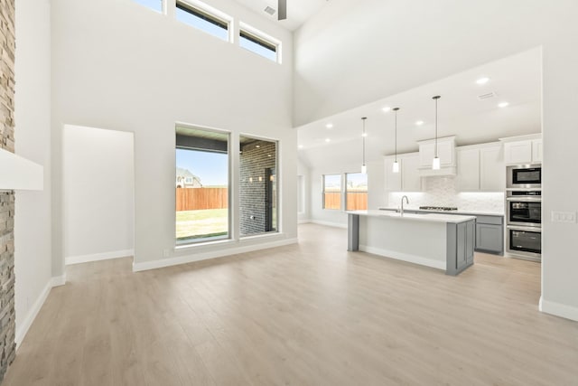 unfurnished living room with light wood-type flooring, a sink, a fireplace, and plenty of natural light