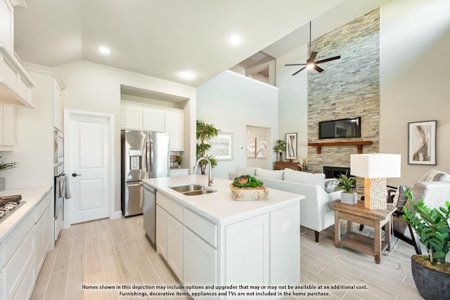 kitchen featuring a kitchen island with sink, sink, a fireplace, and white cabinets