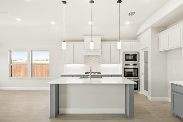 kitchen featuring stainless steel appliances, tasteful backsplash, visible vents, and light countertops