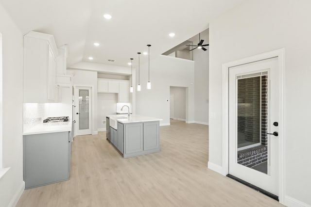kitchen featuring light wood-style flooring, pendant lighting, light countertops, and white cabinets