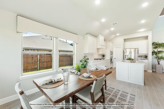 dining space with light hardwood / wood-style flooring and vaulted ceiling