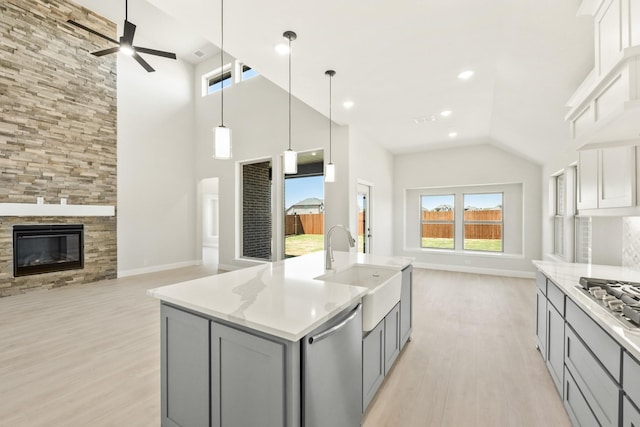 kitchen featuring open floor plan, light wood-style flooring, gray cabinetry, appliances with stainless steel finishes, and a sink