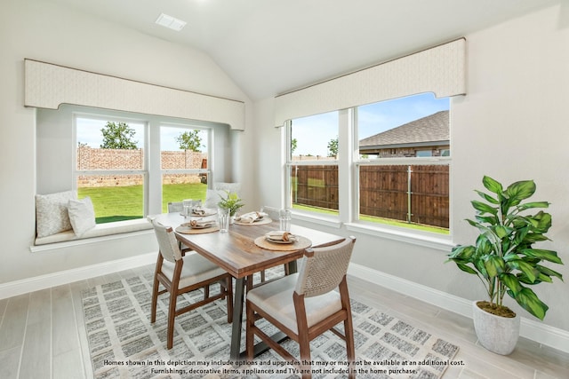 dining space with hardwood / wood-style flooring and vaulted ceiling