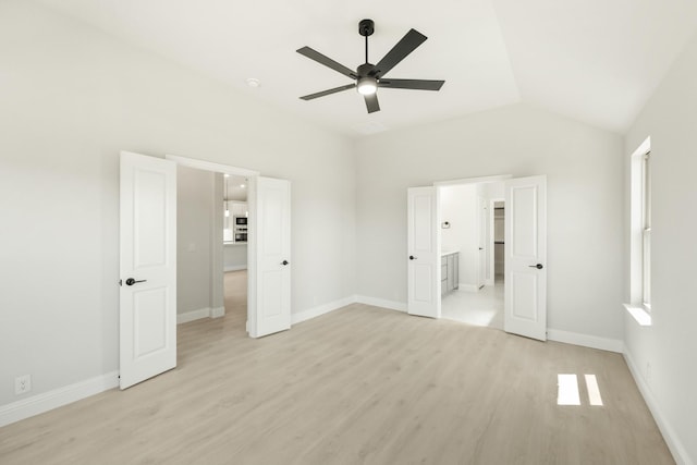 unfurnished bedroom featuring ceiling fan, light wood-type flooring, baseboards, and lofted ceiling