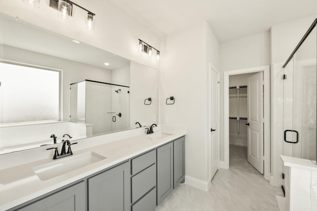 bathroom featuring a sink, a spacious closet, a shower stall, and double vanity