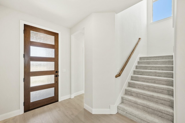 foyer entrance with baseboards, stairway, and wood finished floors