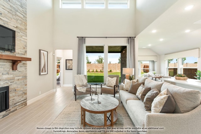 living room with a towering ceiling, a fireplace, and light hardwood / wood-style flooring