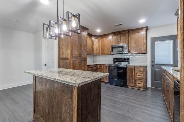 kitchen featuring dark hardwood / wood-style floors, backsplash, decorative light fixtures, a kitchen island, and black appliances