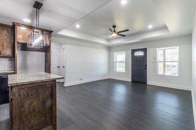 kitchen featuring dark wood-style floors, backsplash, a center island, and a raised ceiling