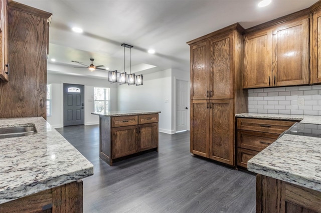 kitchen with decorative backsplash, ceiling fan, dark wood-type flooring, and hanging light fixtures