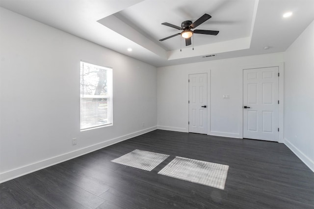 unfurnished bedroom featuring dark hardwood / wood-style floors, a raised ceiling, and ceiling fan