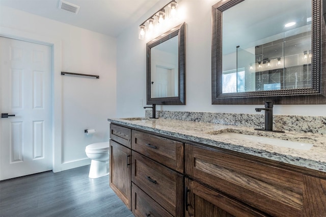 bathroom with walk in shower, hardwood / wood-style floors, vanity, and toilet