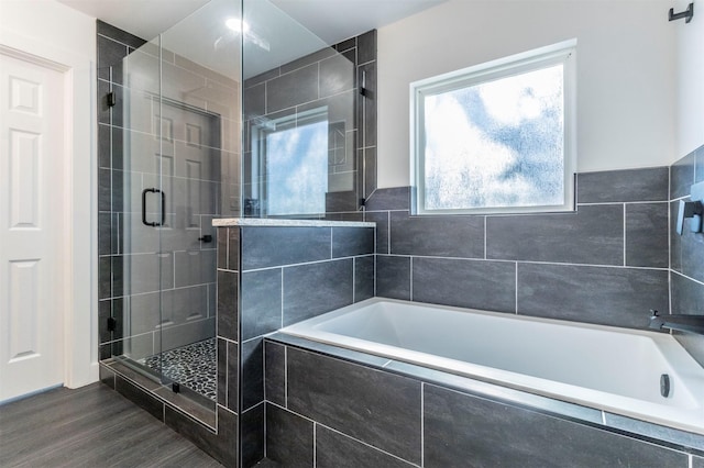 bathroom with a shower stall, a garden tub, and wood finished floors