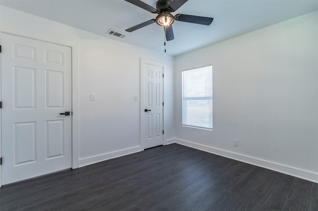 unfurnished bedroom featuring dark wood finished floors, baseboards, visible vents, and a ceiling fan