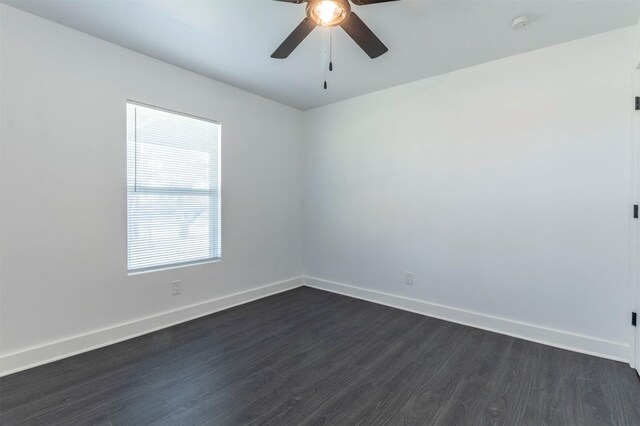 spare room with baseboards, dark wood finished floors, and a ceiling fan