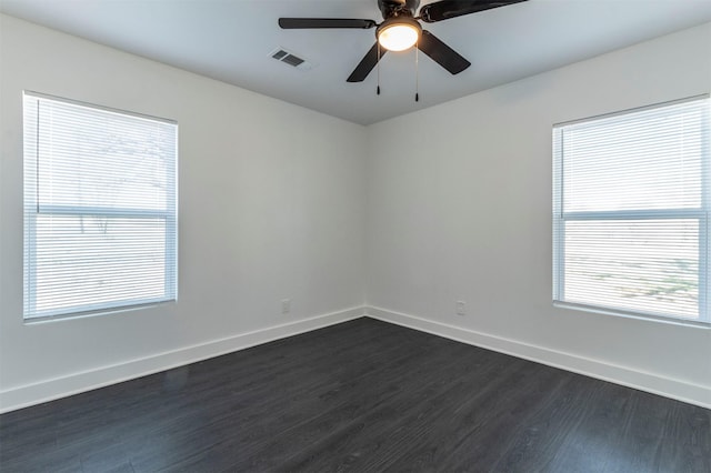 spare room with dark wood finished floors, visible vents, ceiling fan, and baseboards