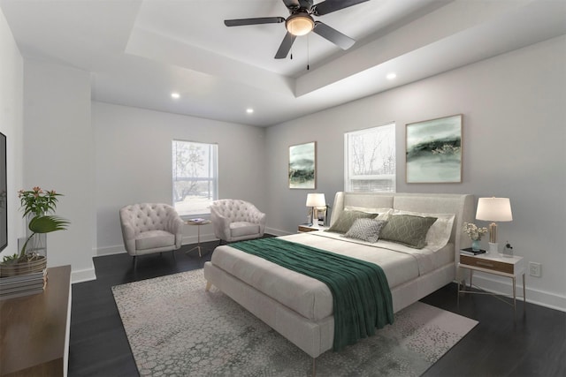 bedroom with a tray ceiling, baseboards, and dark wood-type flooring