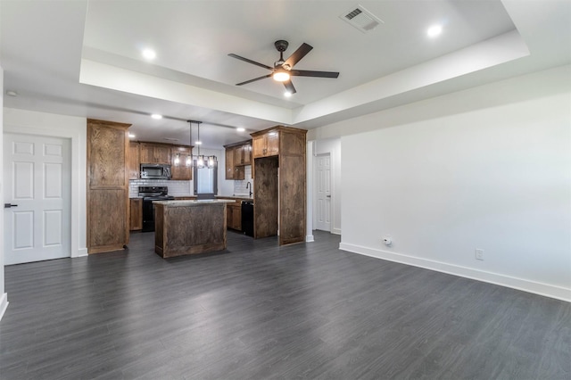 kitchen with a kitchen island, baseboards, open floor plan, a tray ceiling, and black appliances